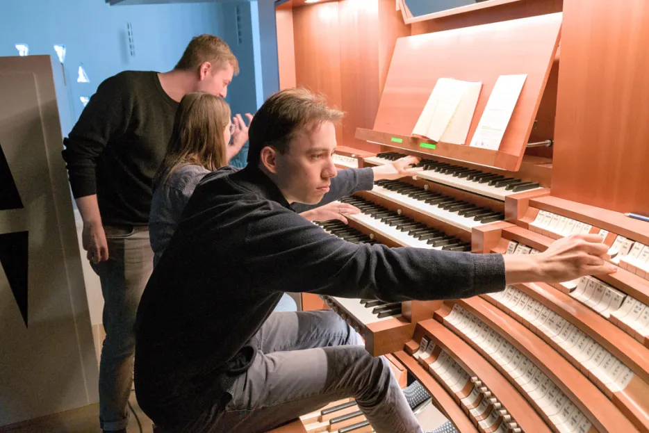 Drei Studierende sitzen an einem großen Orgelspieltisch