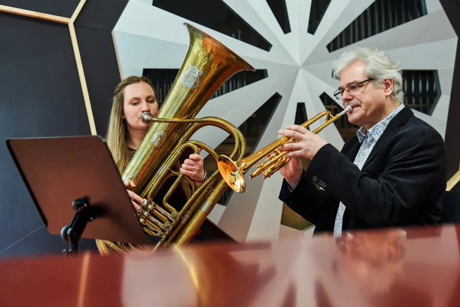 Studentin mit Tuba neben Dozent mit Trompete
